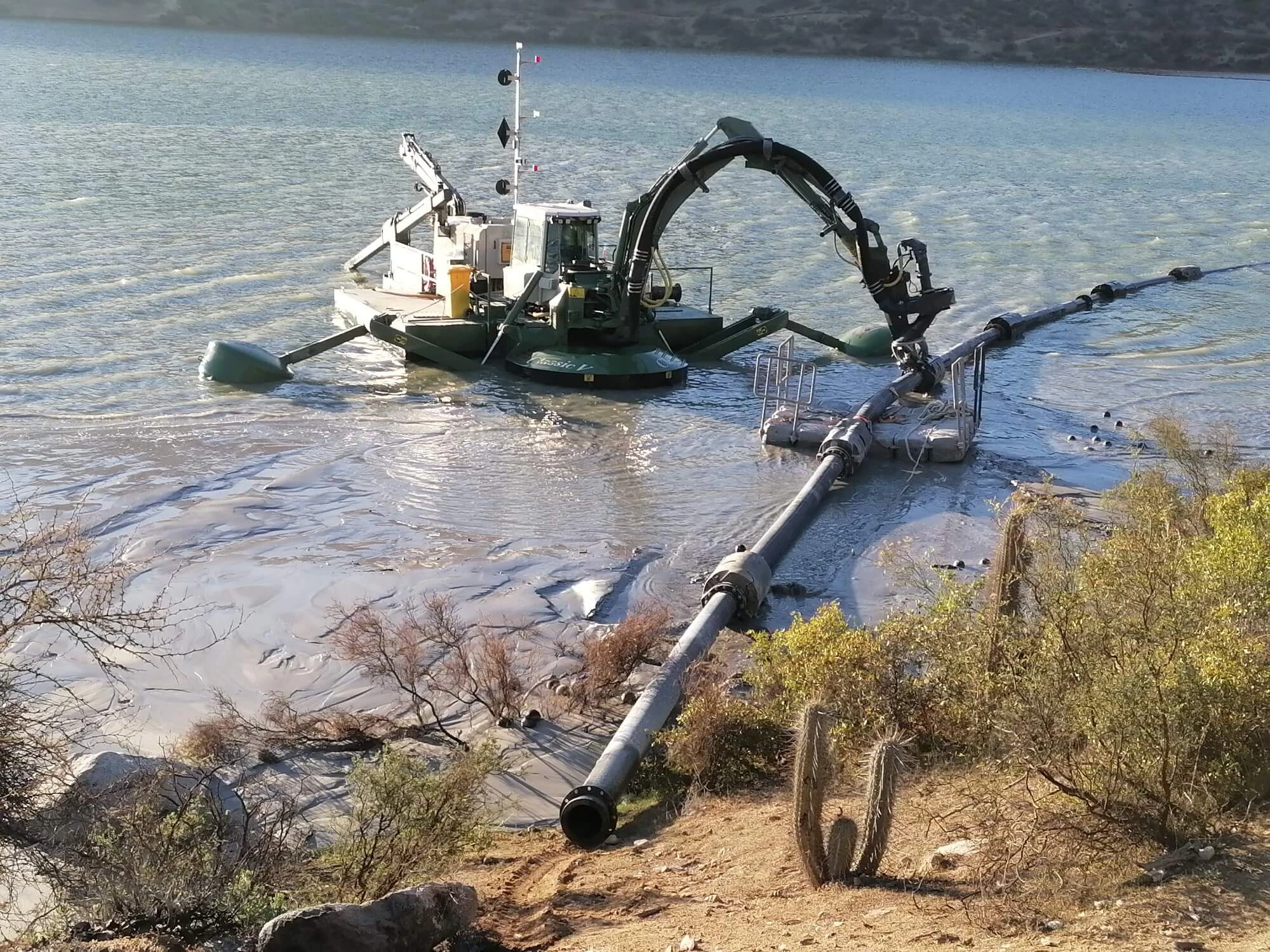Draga especializada trabajando en una laguna de aguas claras dentro de un tranque de relaves para recuperar agua y redistribuir sedimentos.