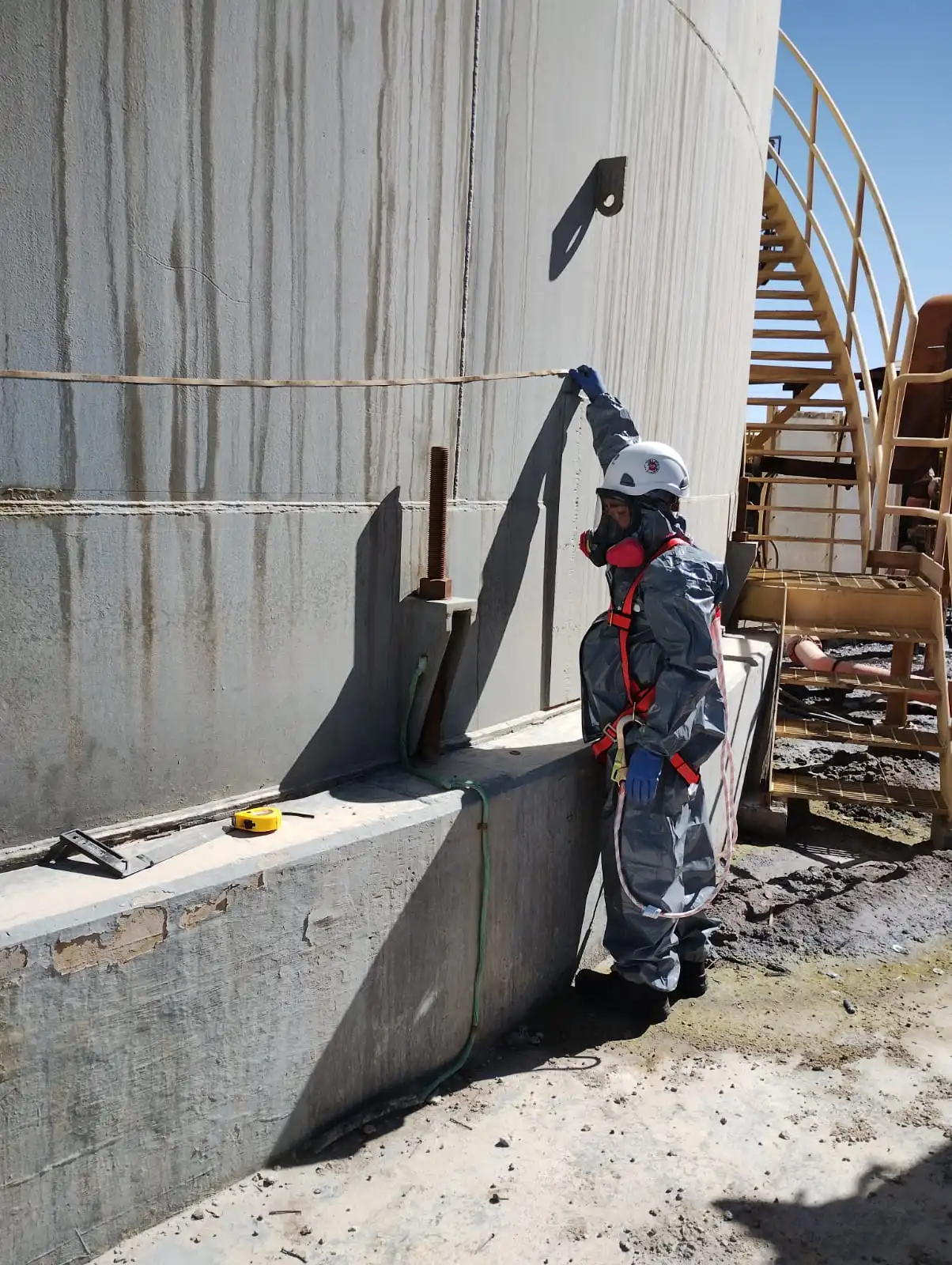 Especialista realizando inspección técnica en un estanque industrial durante trabajos de limpieza y preparación para pruebas operacionales.