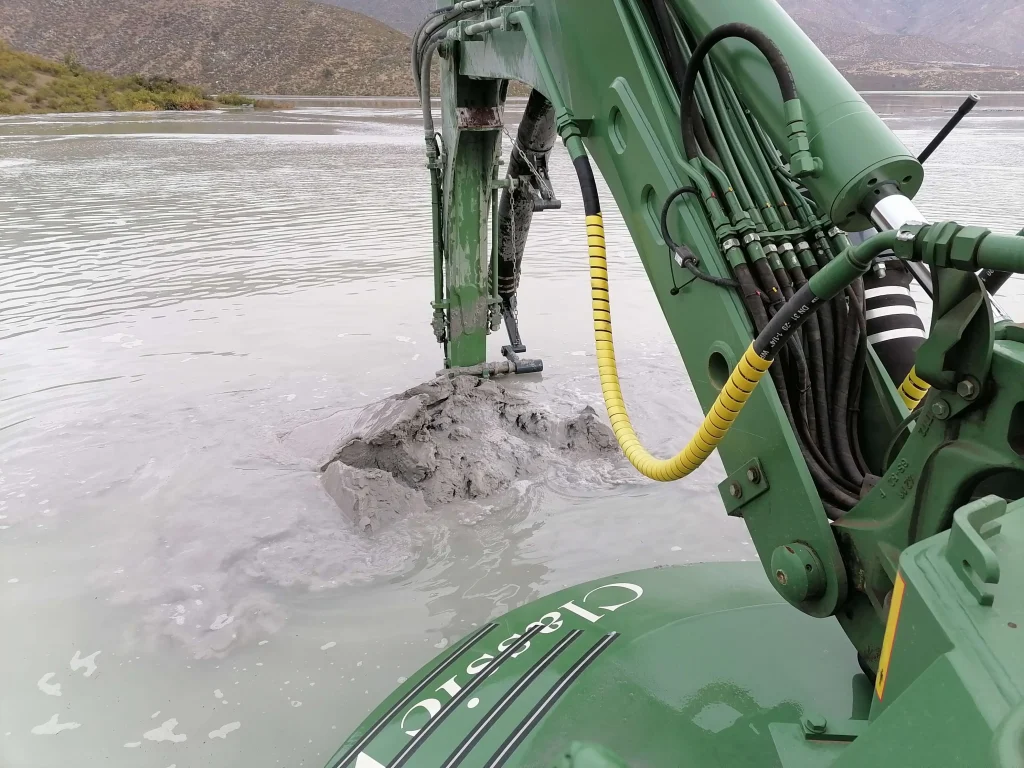 Brazo de draga anfibia Watermaster removiendo sedimentos en una laguna industrial para mejorar la eficiencia hídrica y la sostenibilidad operacional.