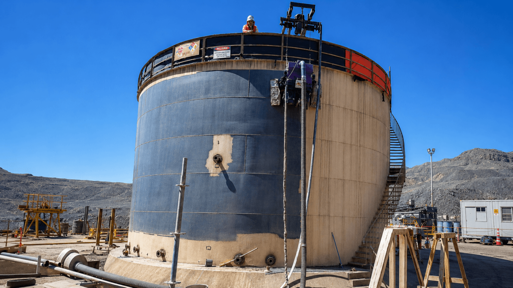 Trabajador realizando limpieza interior de estanque industrial bajo procedimiento de seguridad.